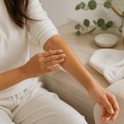 Woman applying Nulela Firming Gold Gel to forearm during a daily body-care ritual